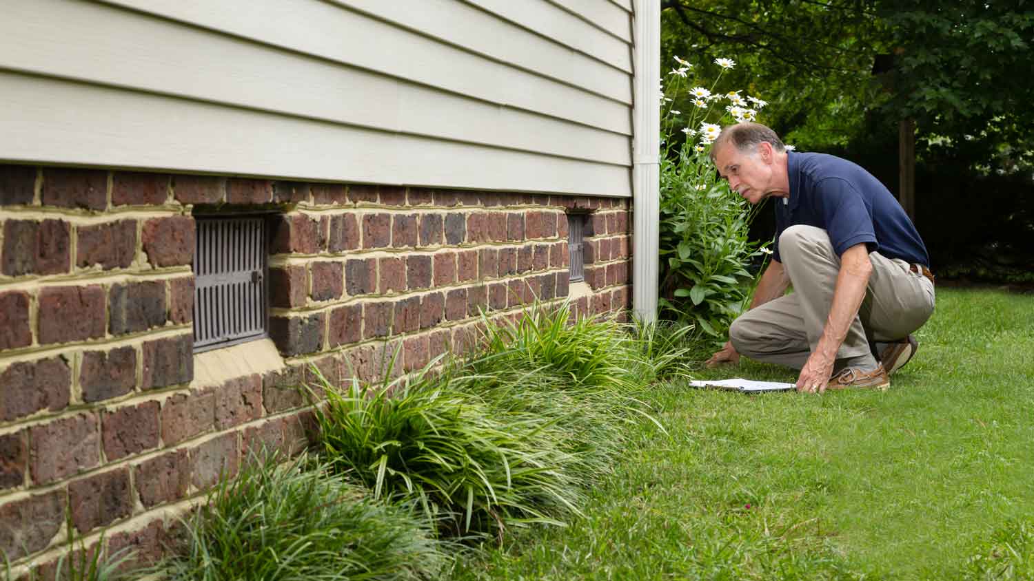 A senior man inspecting a house’s foundation