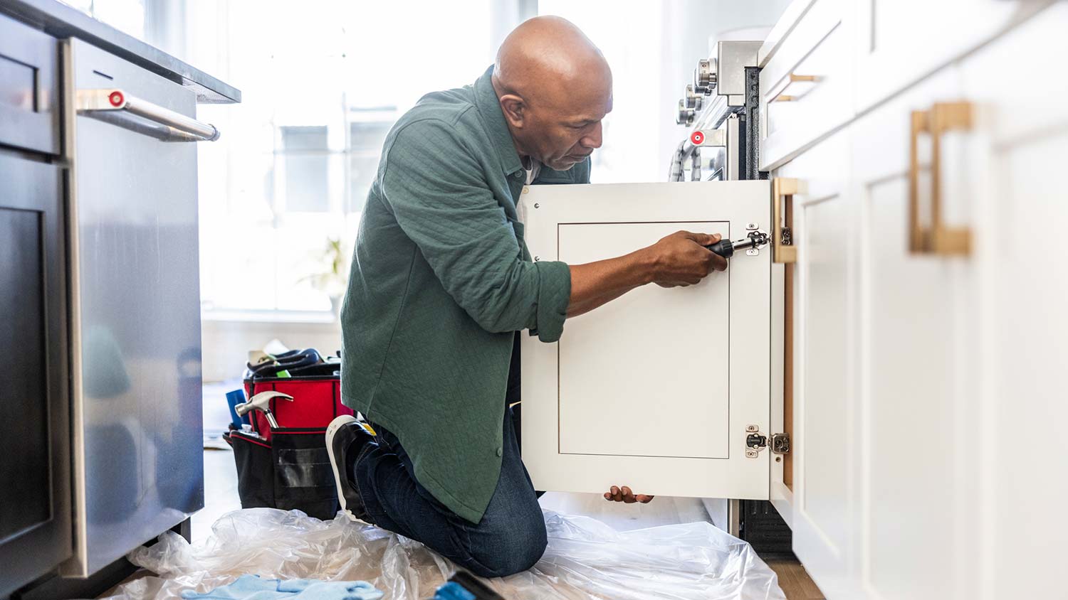 A senior man installing kitchen cabinets