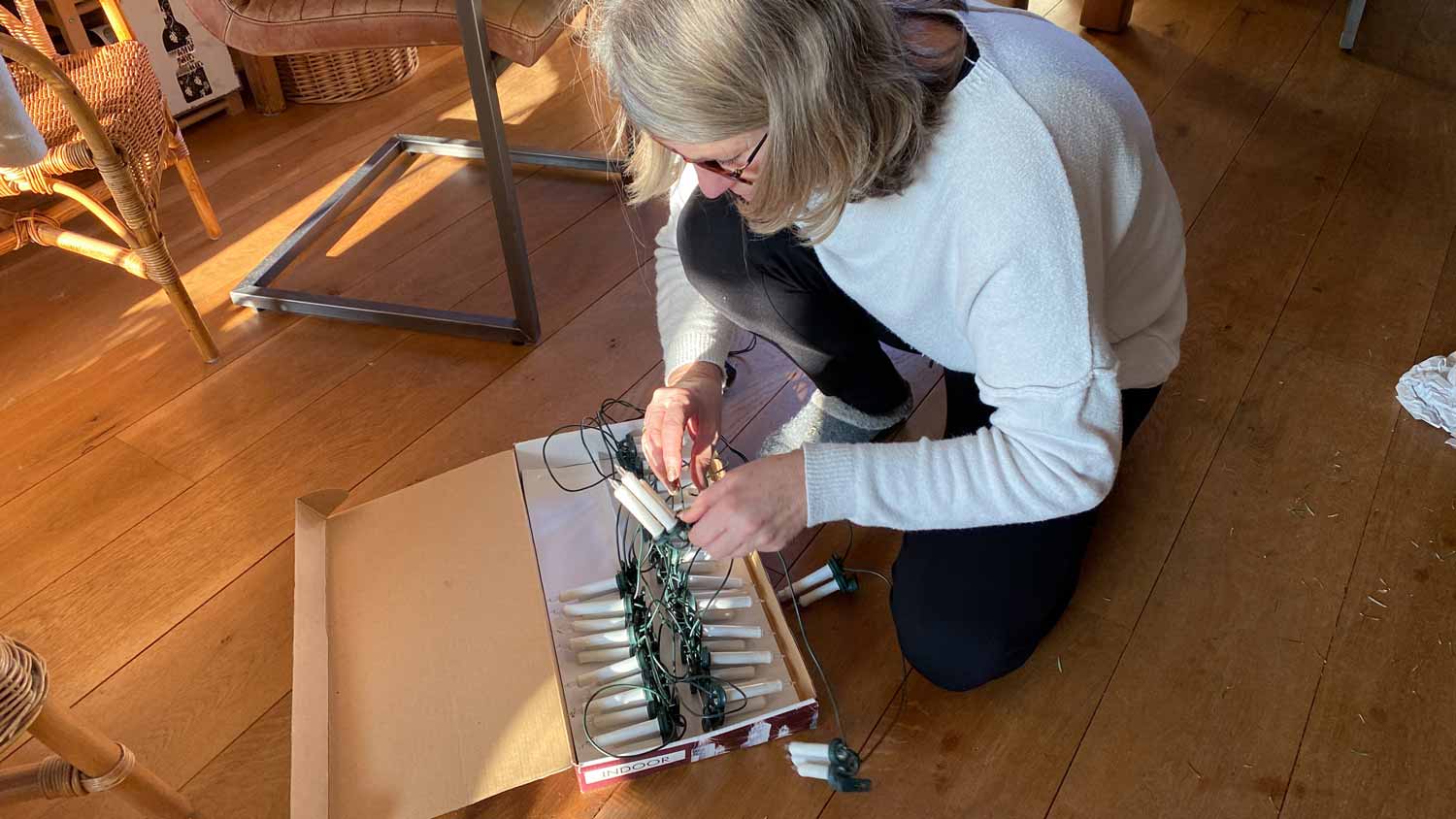 A senior woman packing the christmas lights in the original packaging