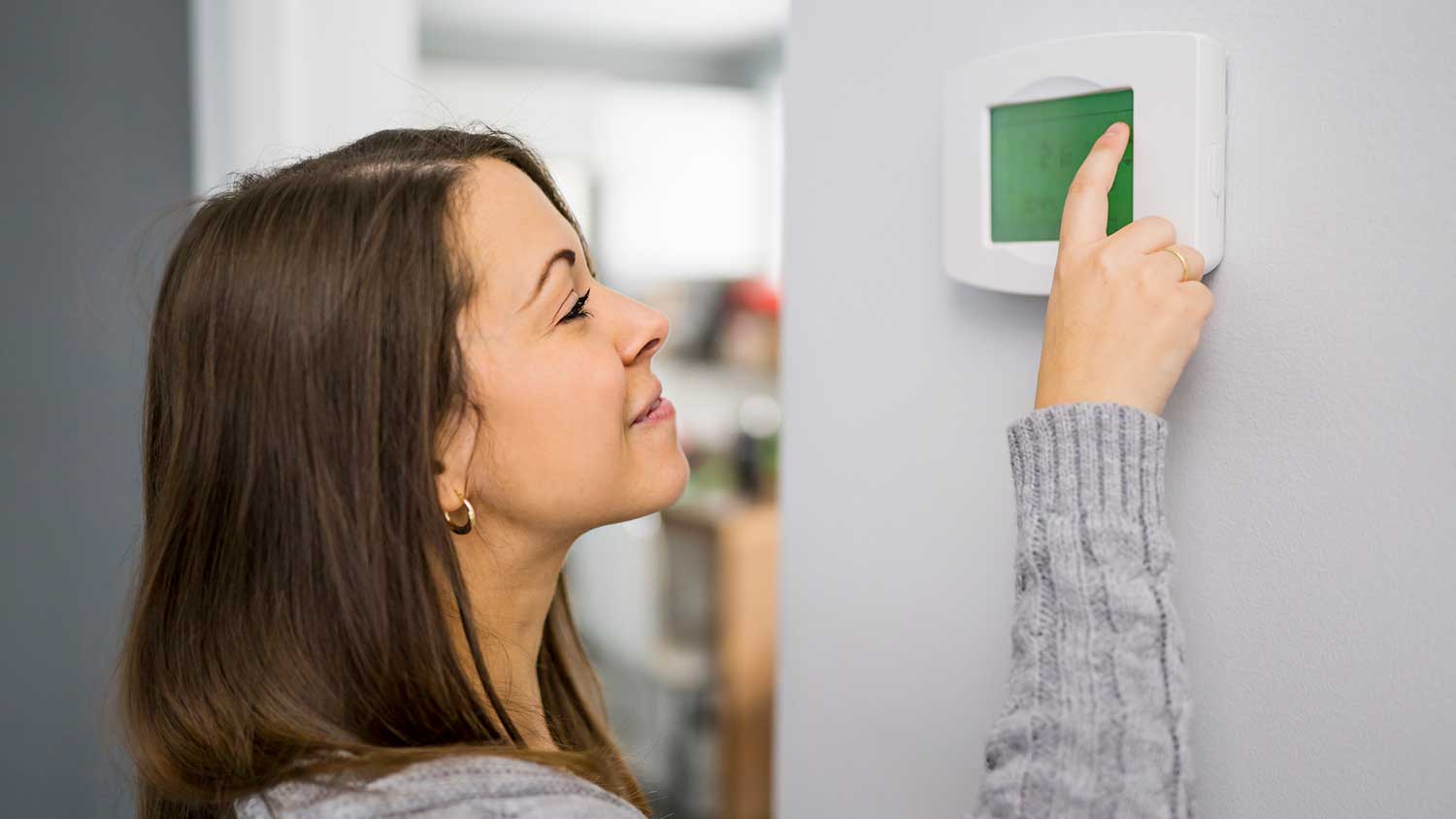 Woman setting up programmable thermostat