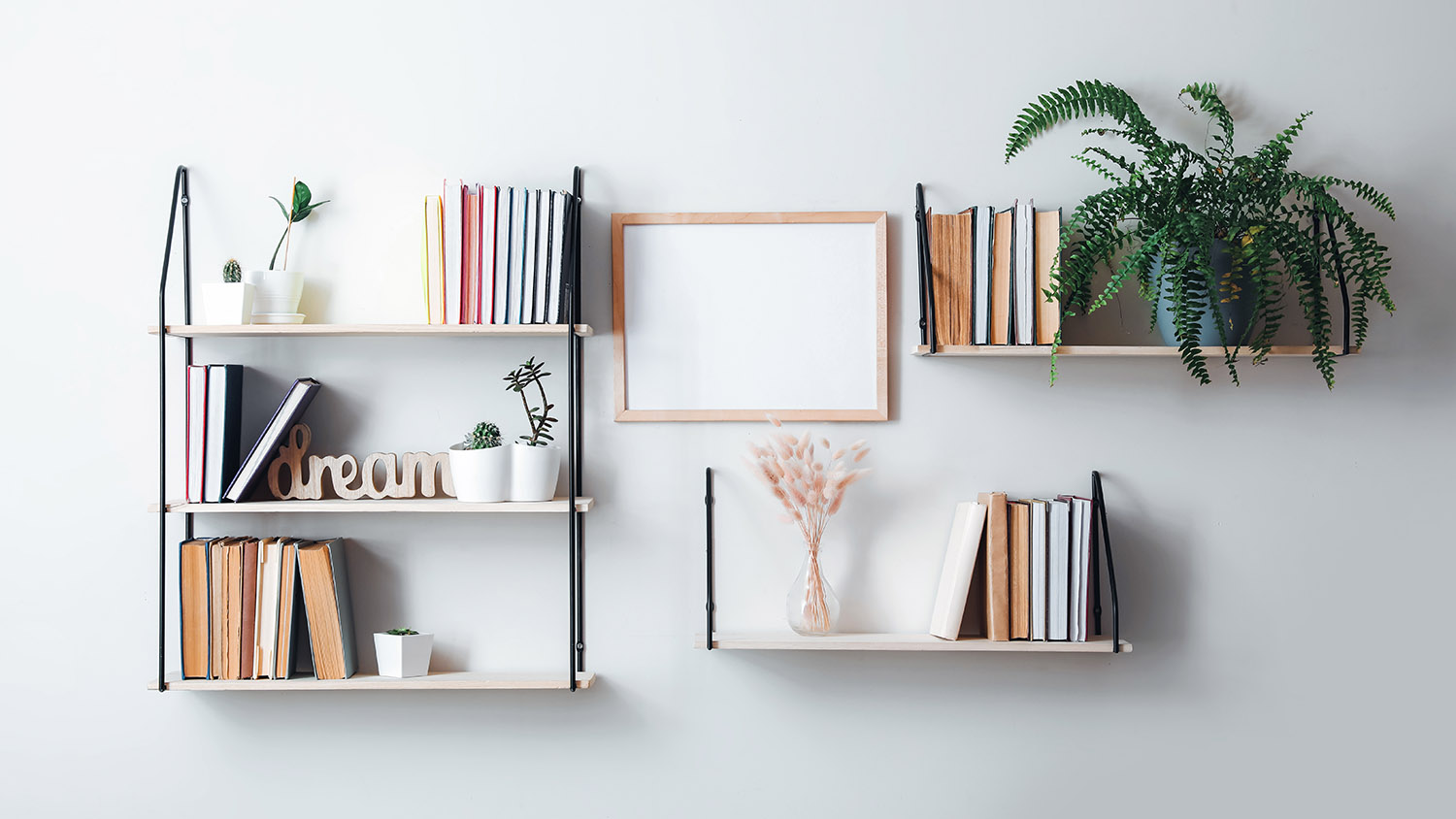 Shelves with books and decor hanging on light wall