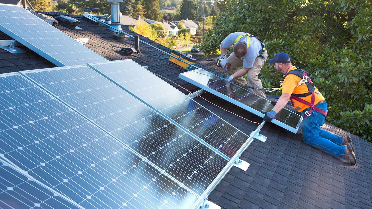 Roofers installing solar panels on asphalt shingle roof