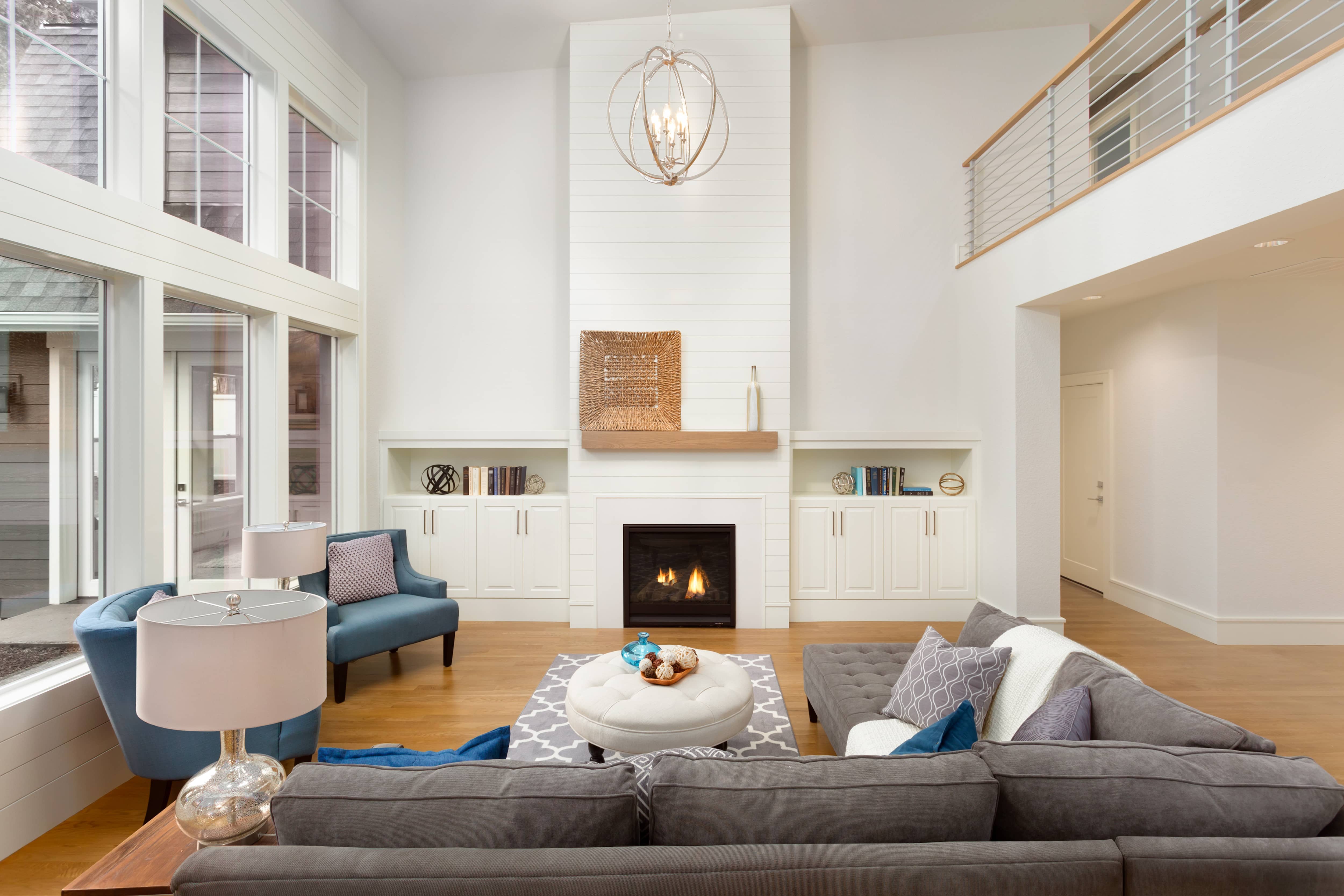 Modern living room with white shiplap fireplace, gray couch, blue chairs, and modern farmhouse chandelier