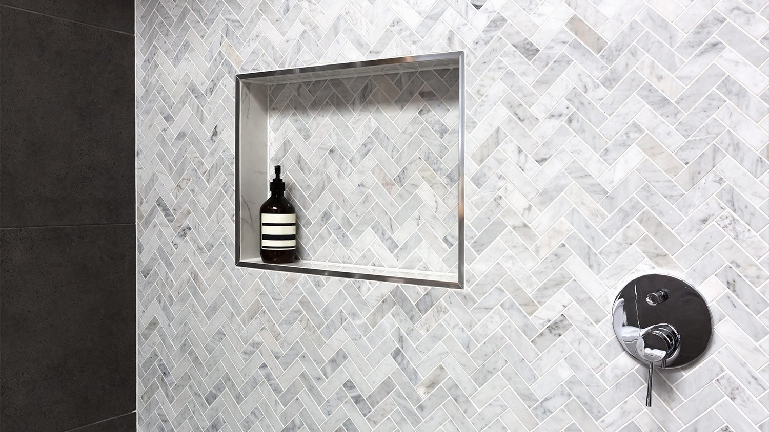 tiled shower niche with black shampoo bottle