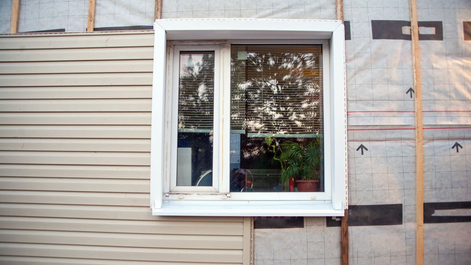 Wall covering of the frame house with panels of vinyl siding of gray color
