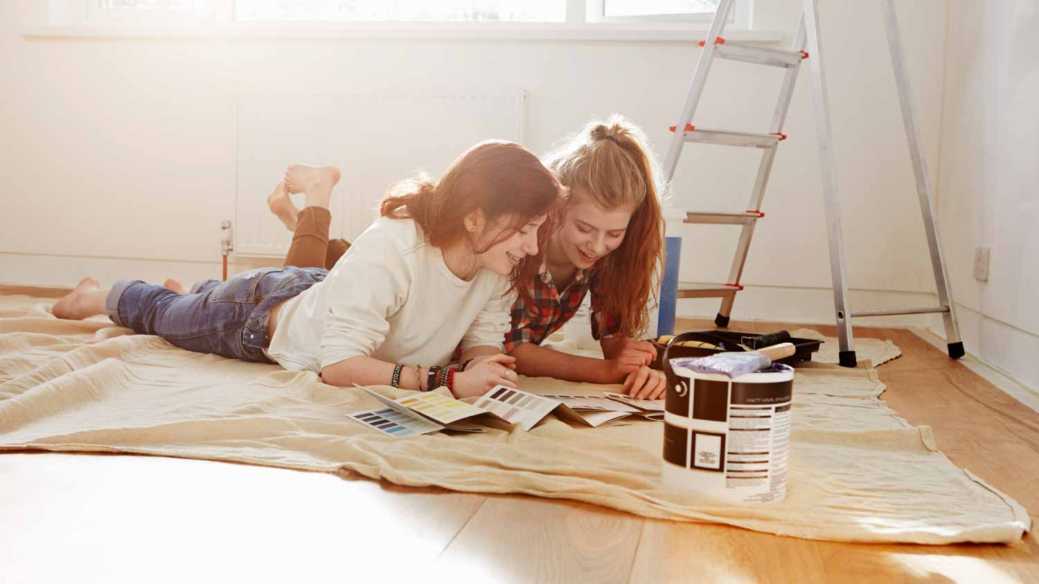 Sisters lying on floor looking at color swatches