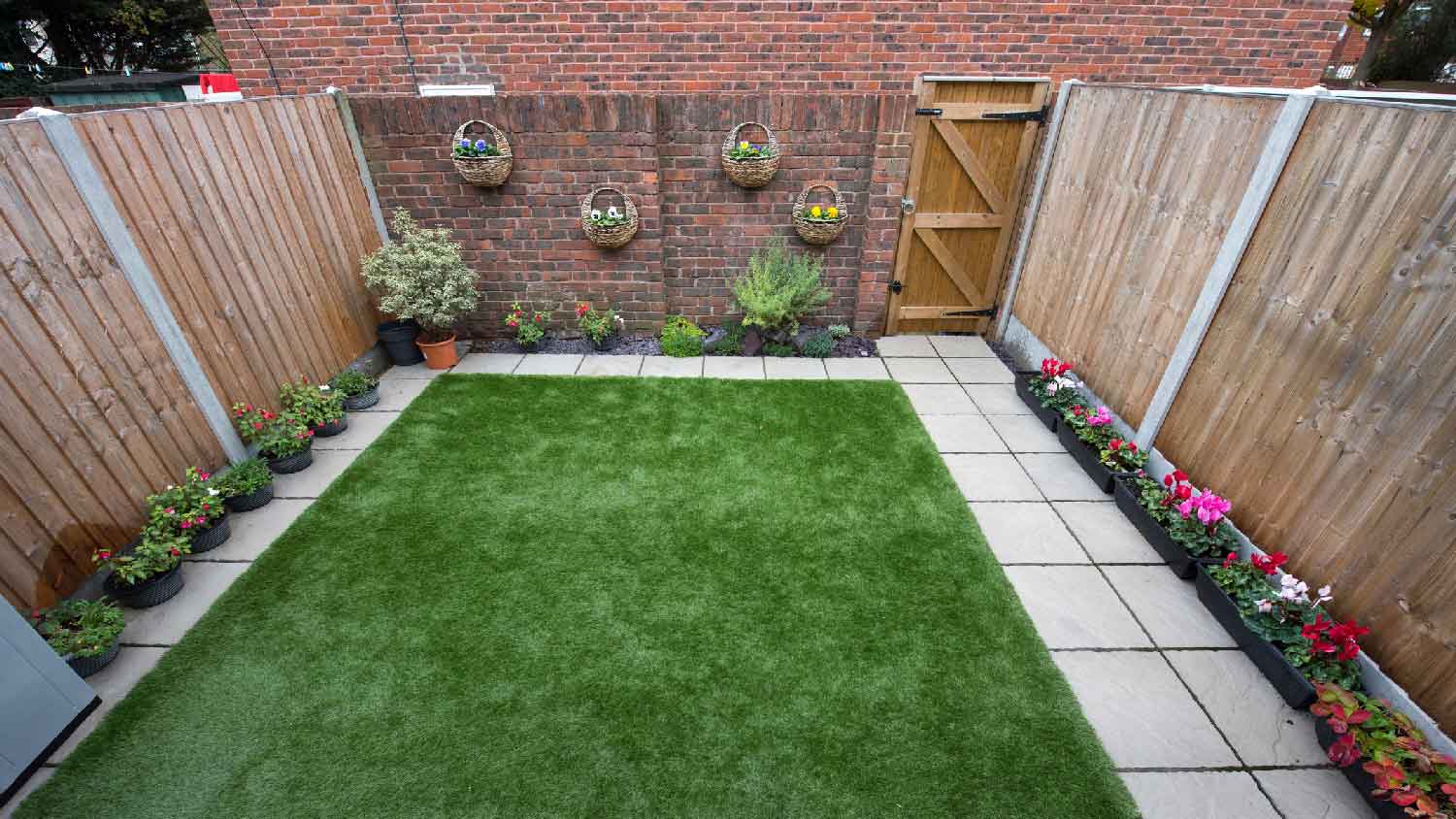 A small backyard with potted flowers on the wooden fence