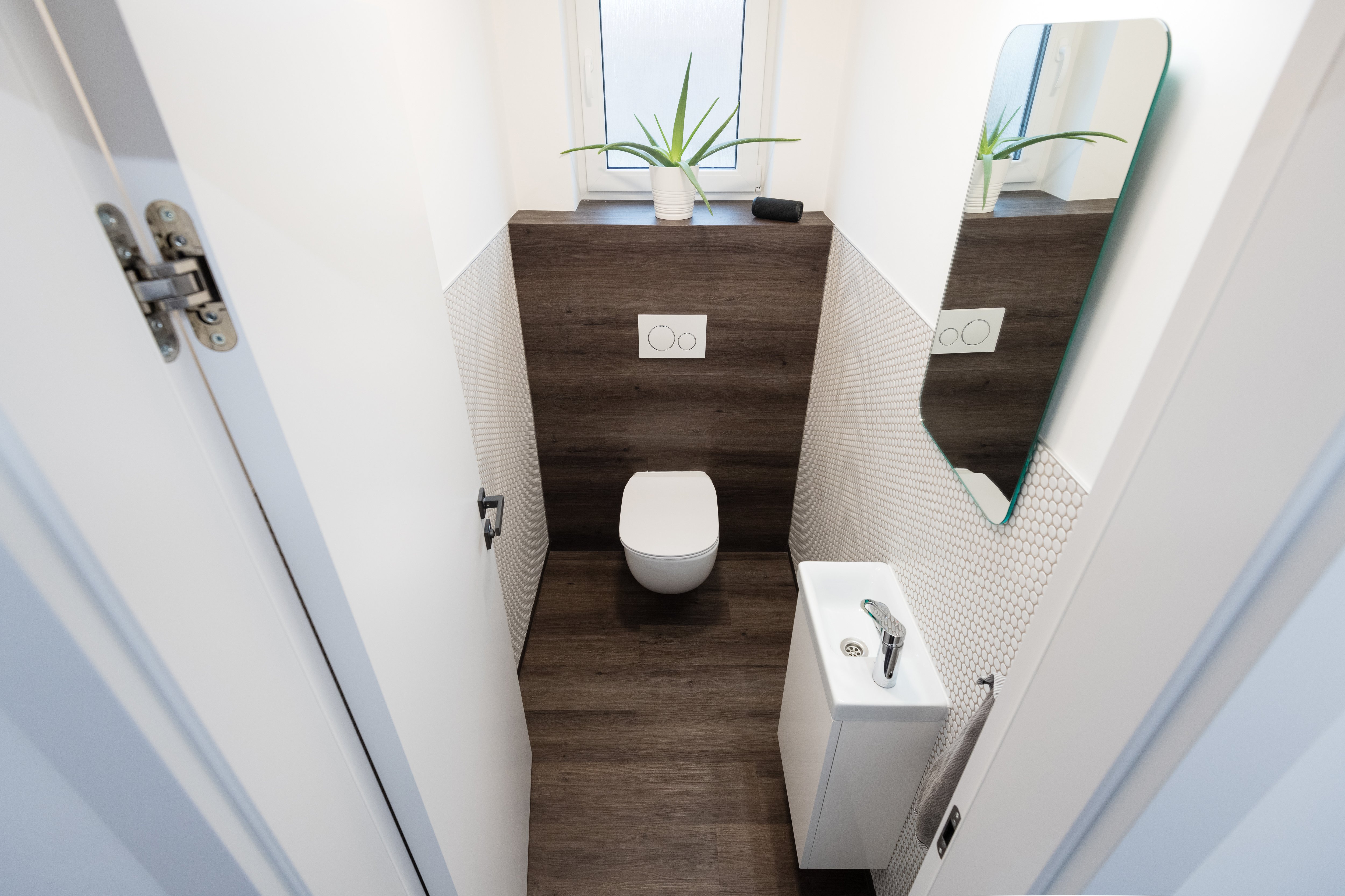 Tiny apartment bathroom bathroom with wood floor and accent wall, wall-hung toilet, honeycomb tiles, and rectangular sink