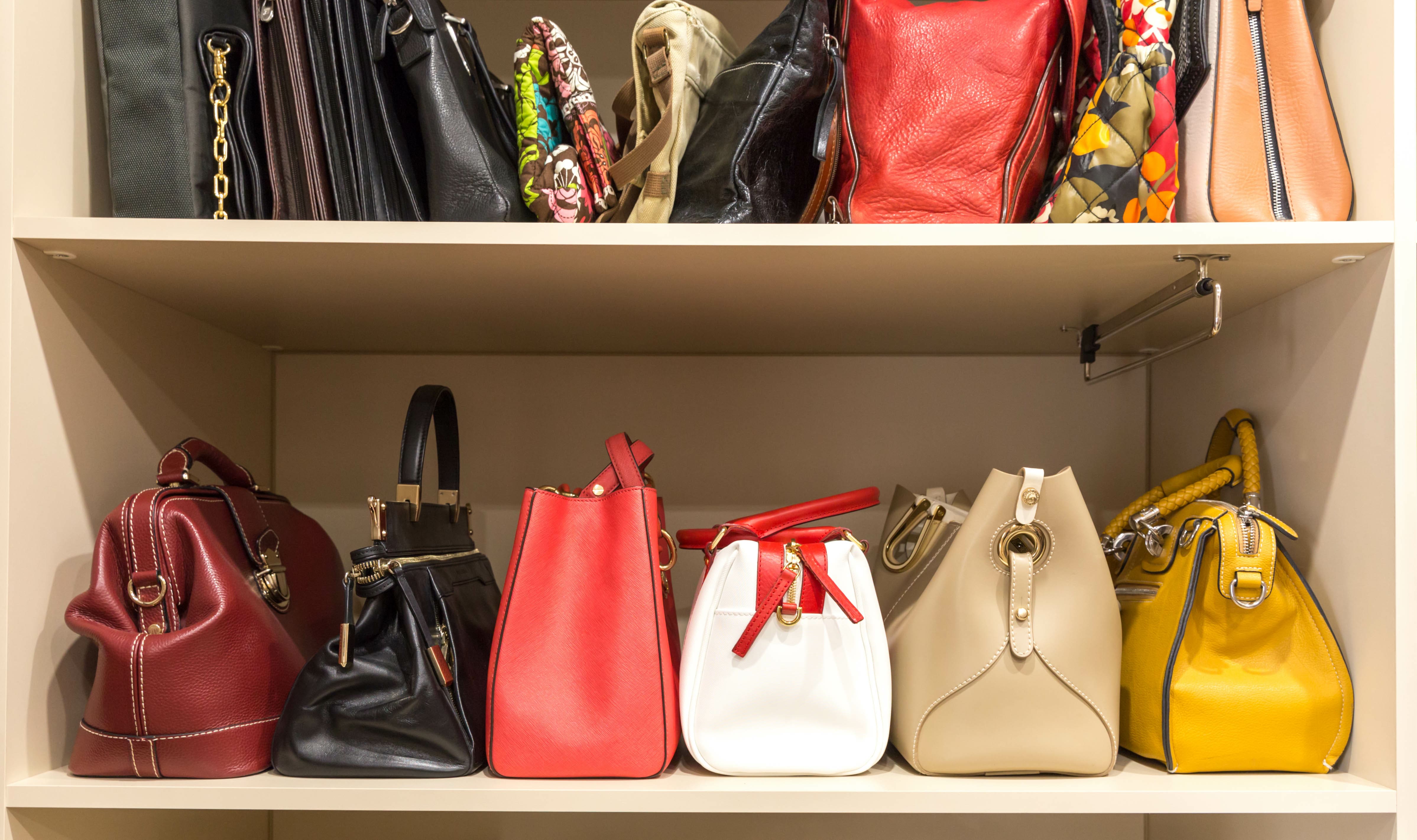 A row of colorful purses on a closet shelf