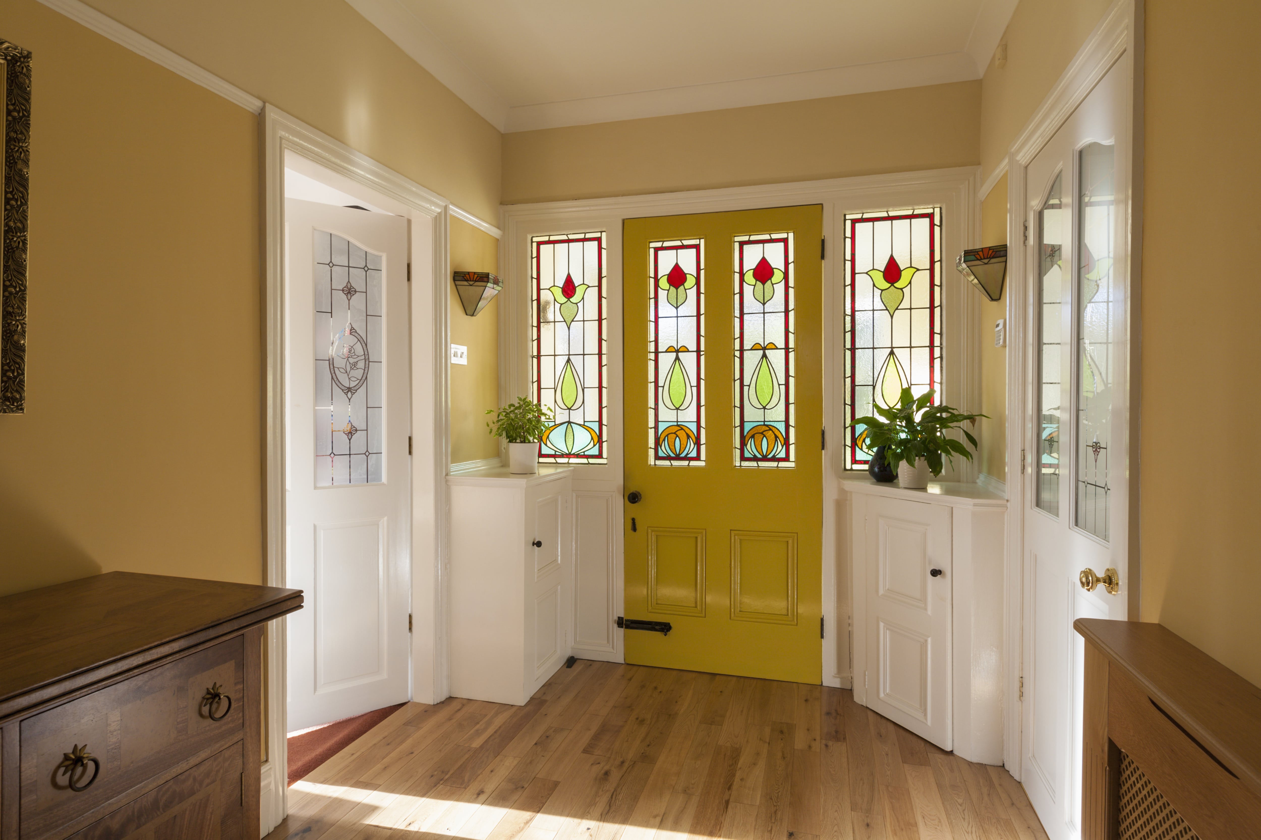 A cozy yellow home entryway with stained glass windows