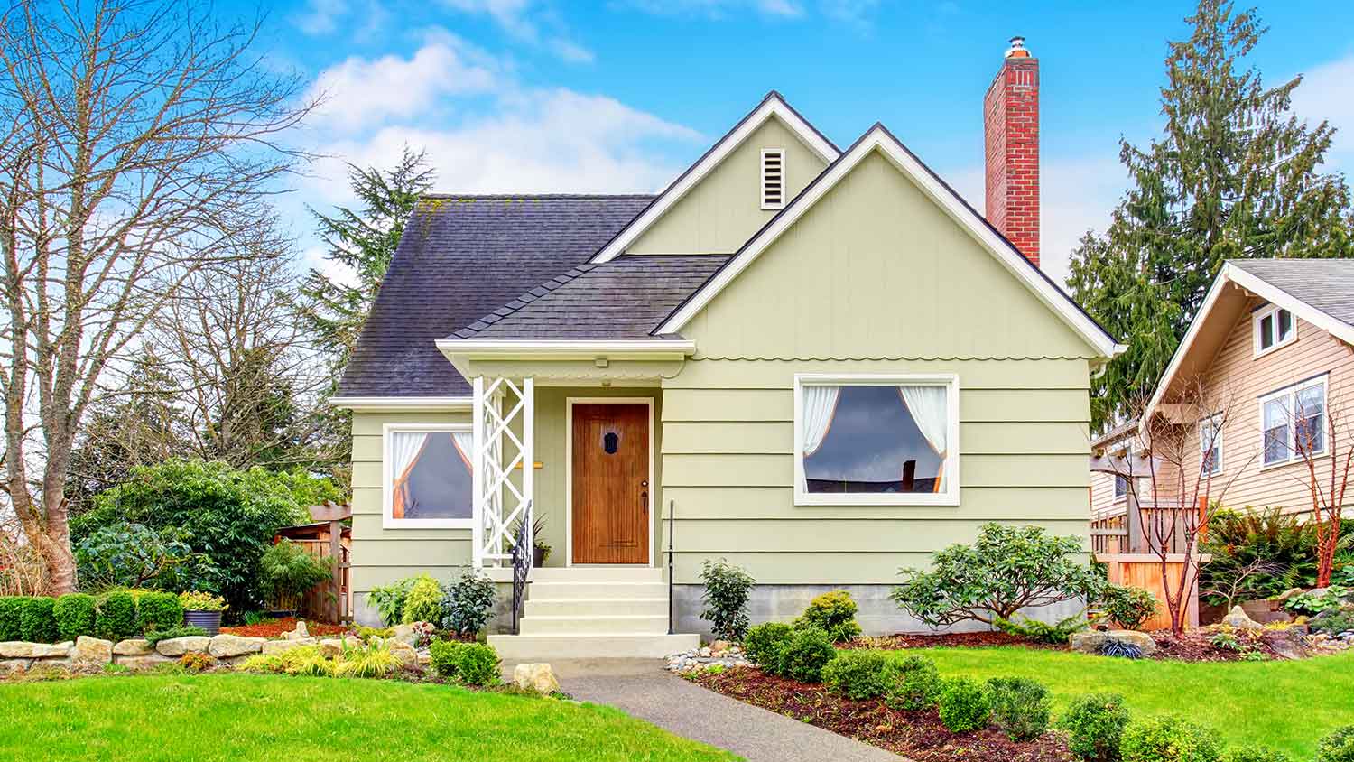 Small house with green siding and brick chimney