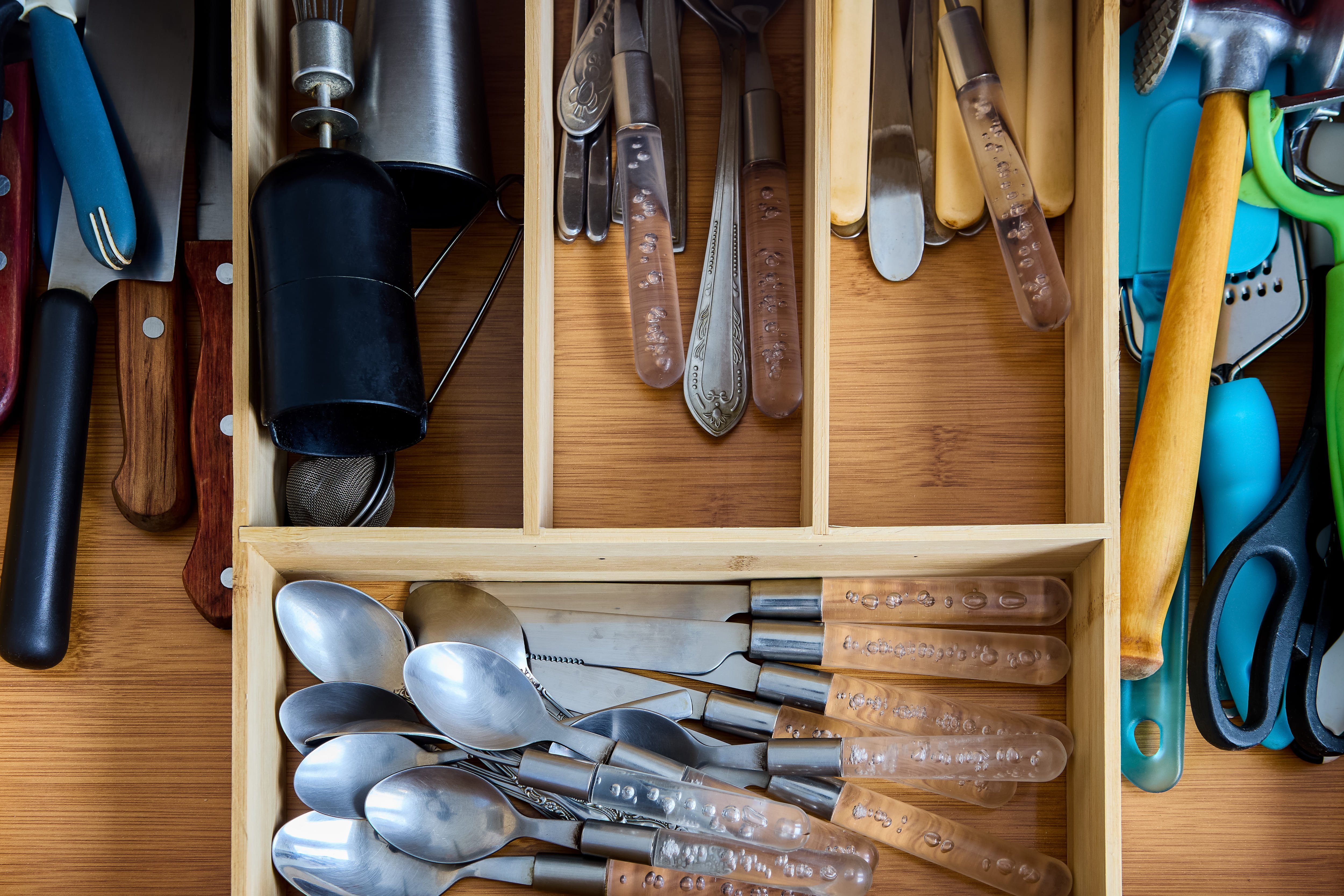 An open drawer with drawer dividers containing silverware