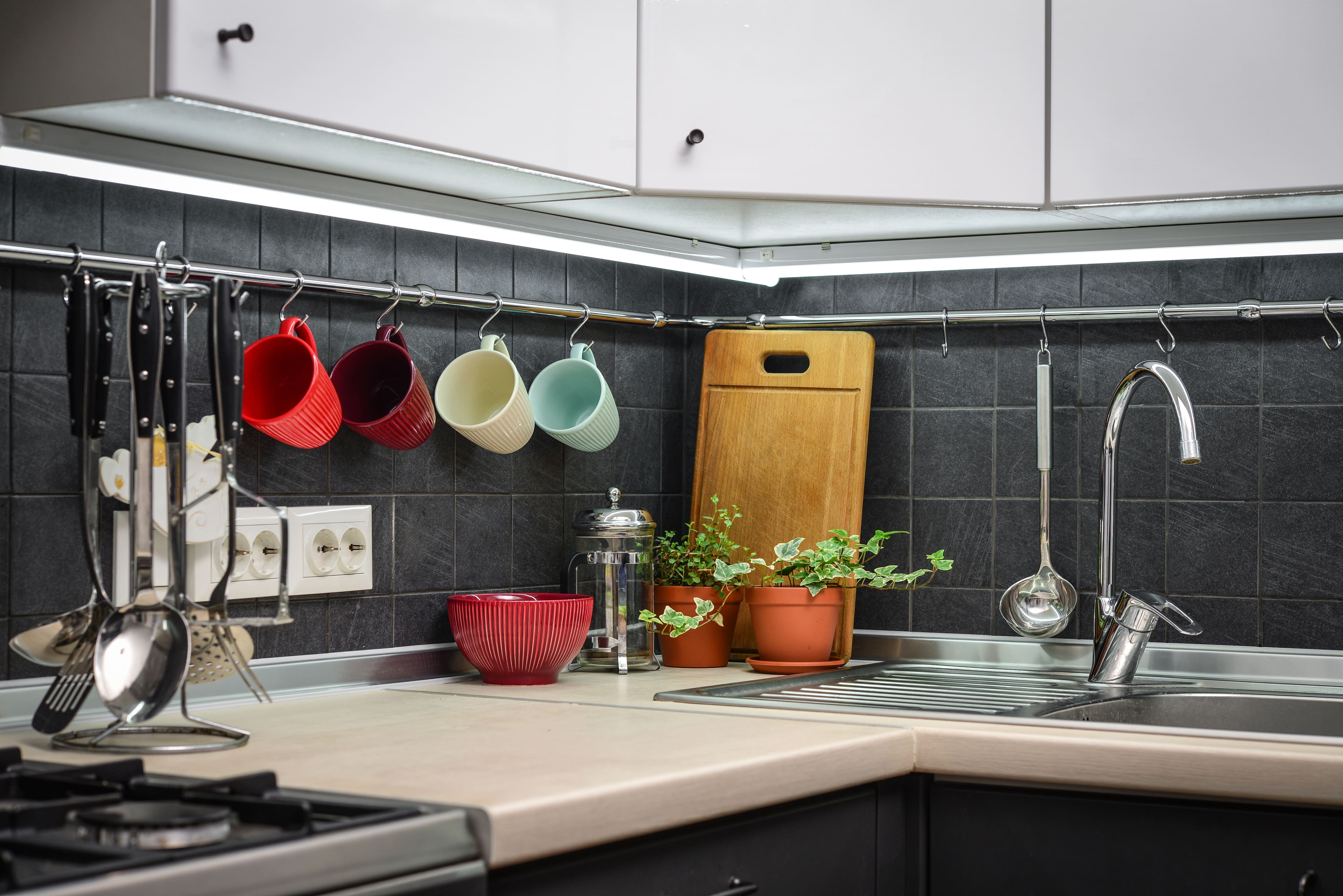 A kitchen counter with a wrap around hanging bar for kitchen utensils