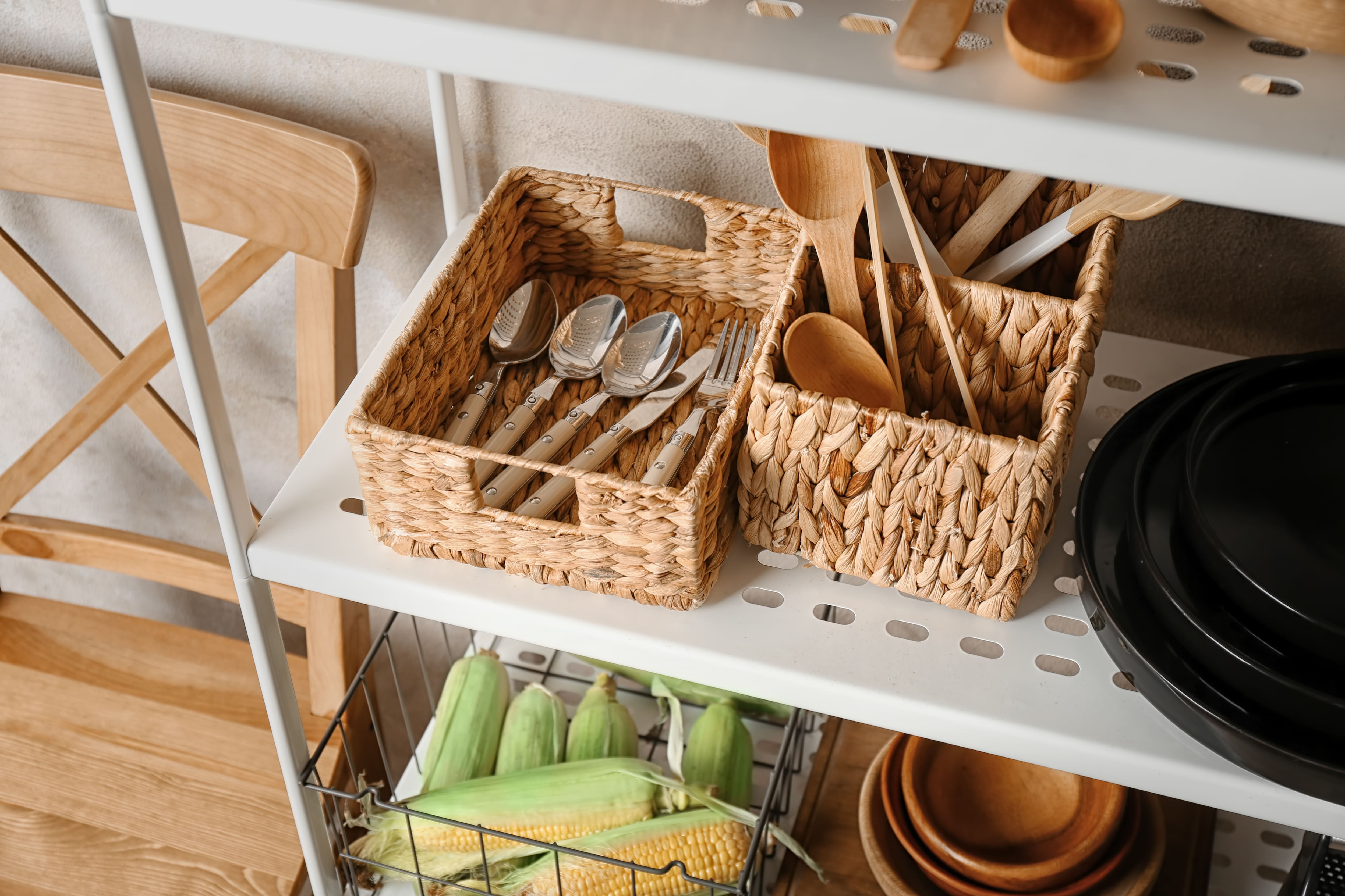 Kitchen utensils stored in wicker baskets on a shelf