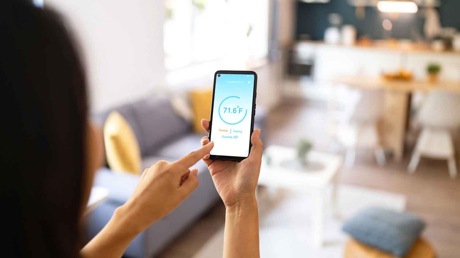 Woman using smart phone to adjust air conditioner