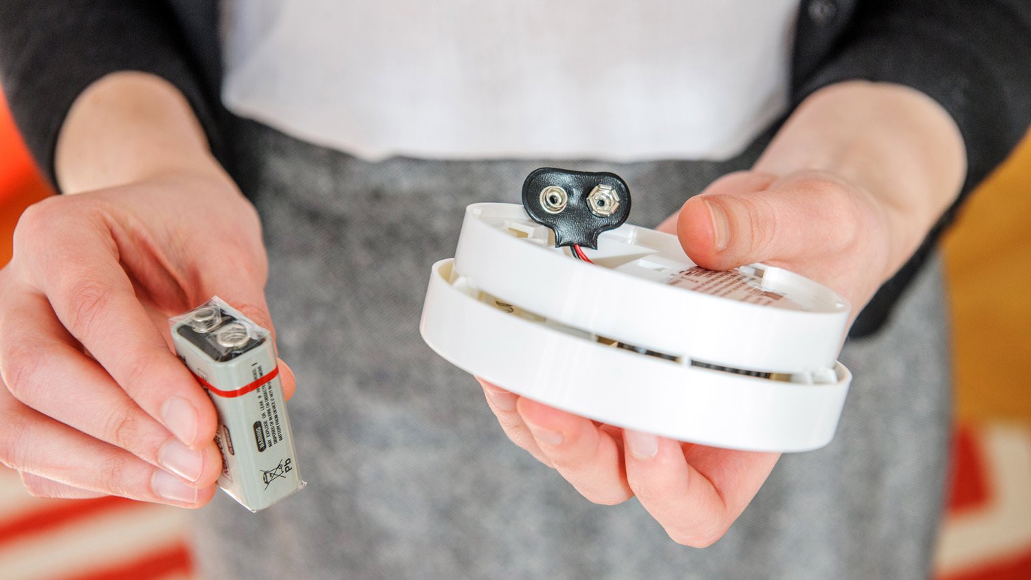 Woman installing 9 volt battery in smoke detector