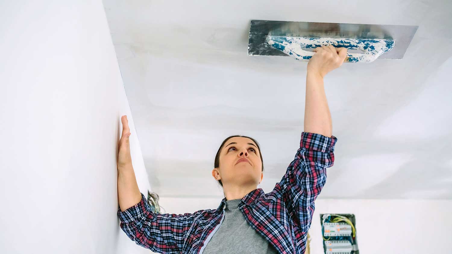 Professional using trowel to smooth a plaster ceiling