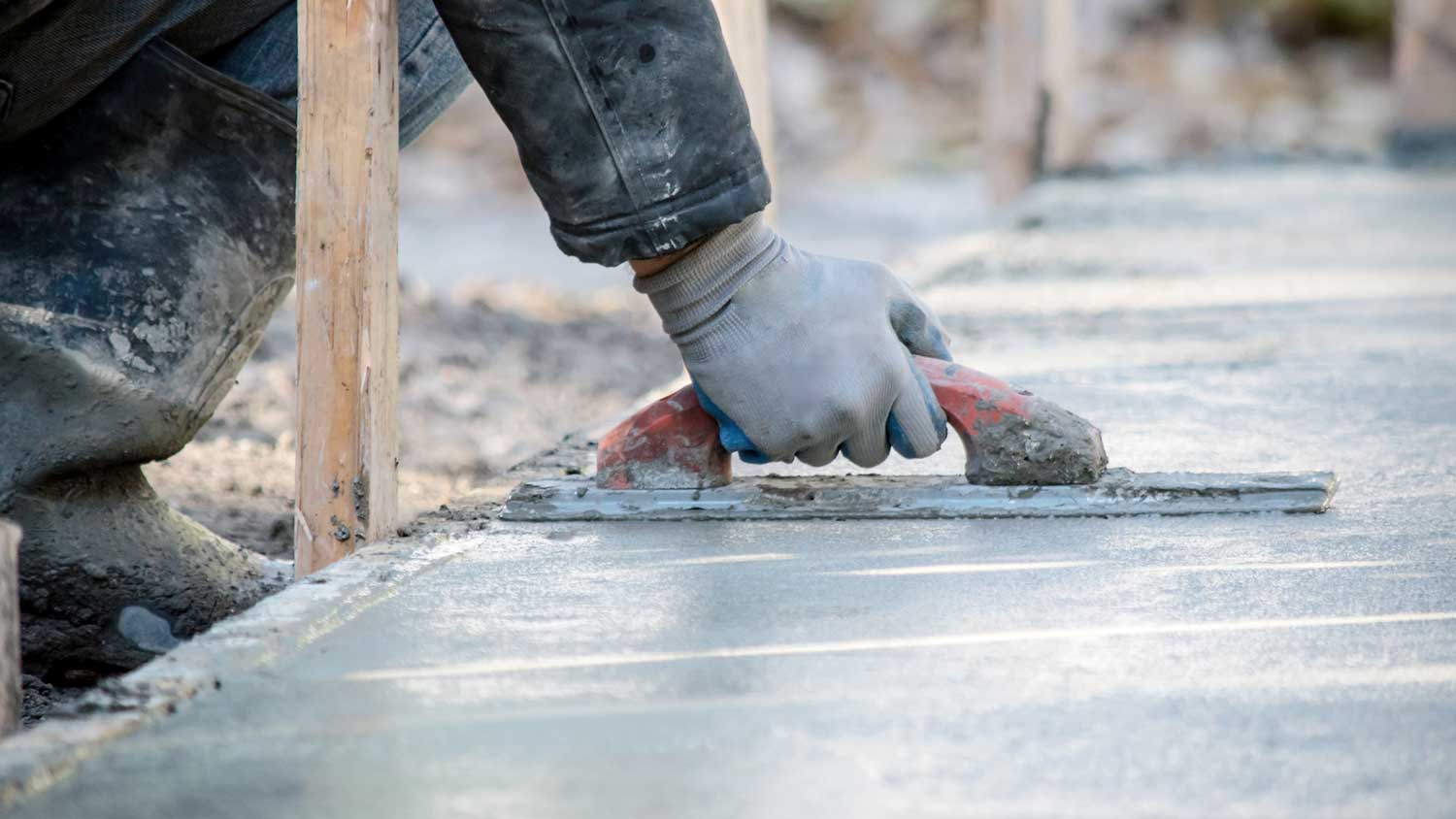 Worker smoothing freshly poured concrete