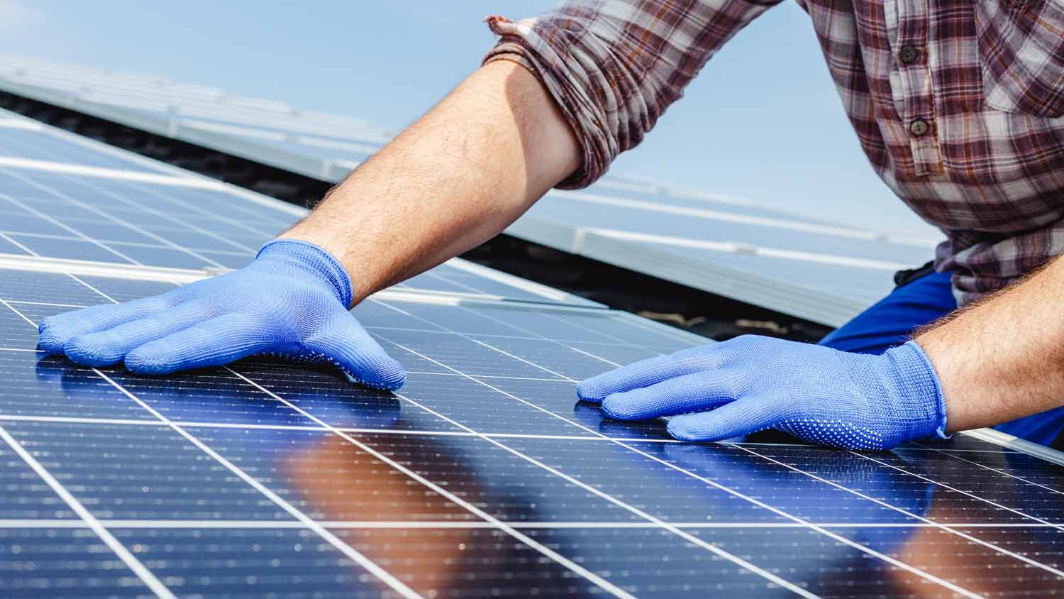 worker touching solar panels