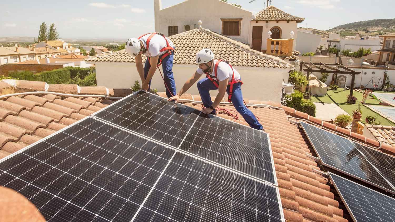 Professional roofers installing solar panels on a tile roof