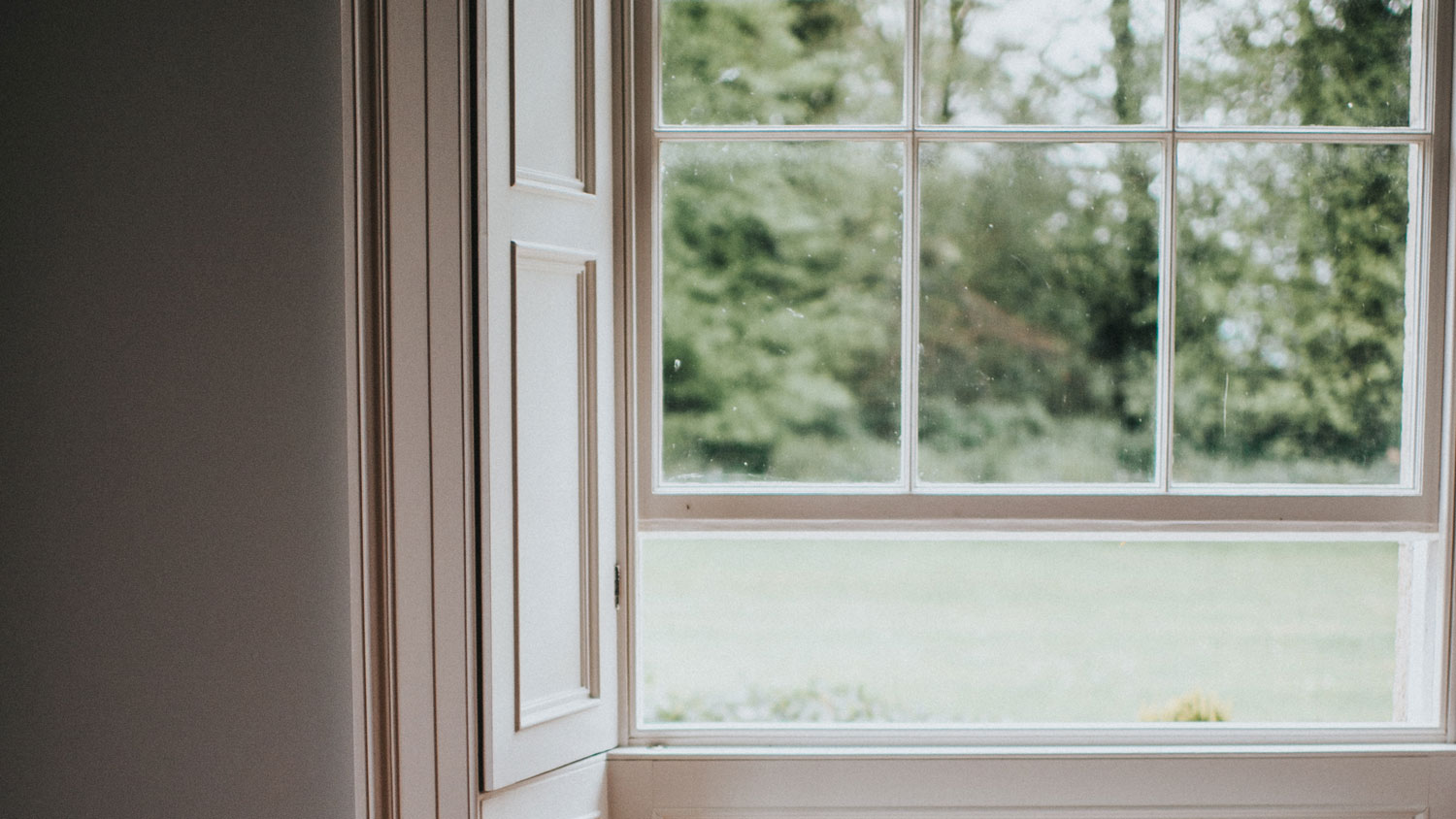 Solid panel shutters on a window looking out at country view