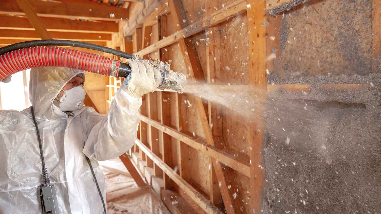 Worker spraying cellulose insulation in the attic