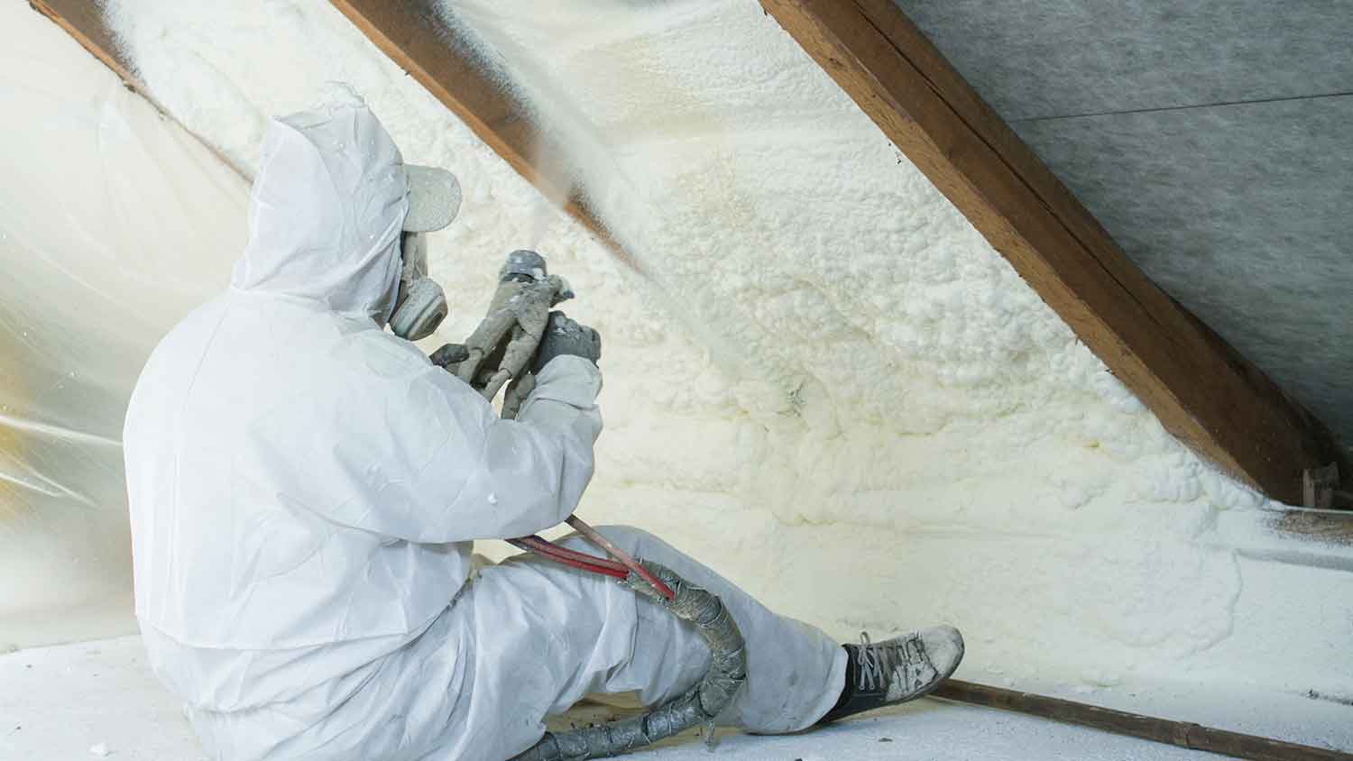 Worker spraying polyurethane foam insulation