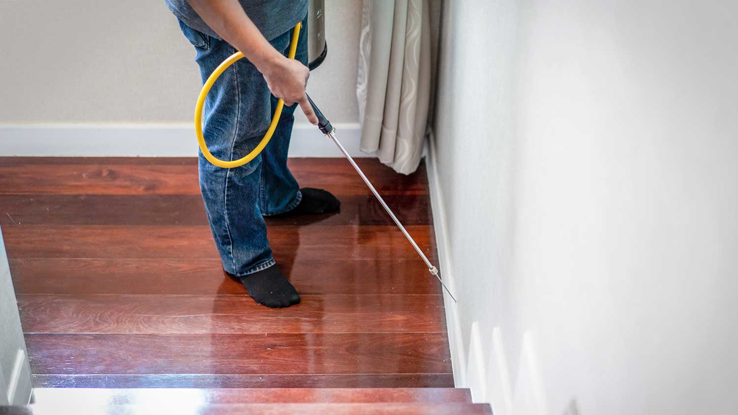 Worker spraying termiticide on wooden staircase