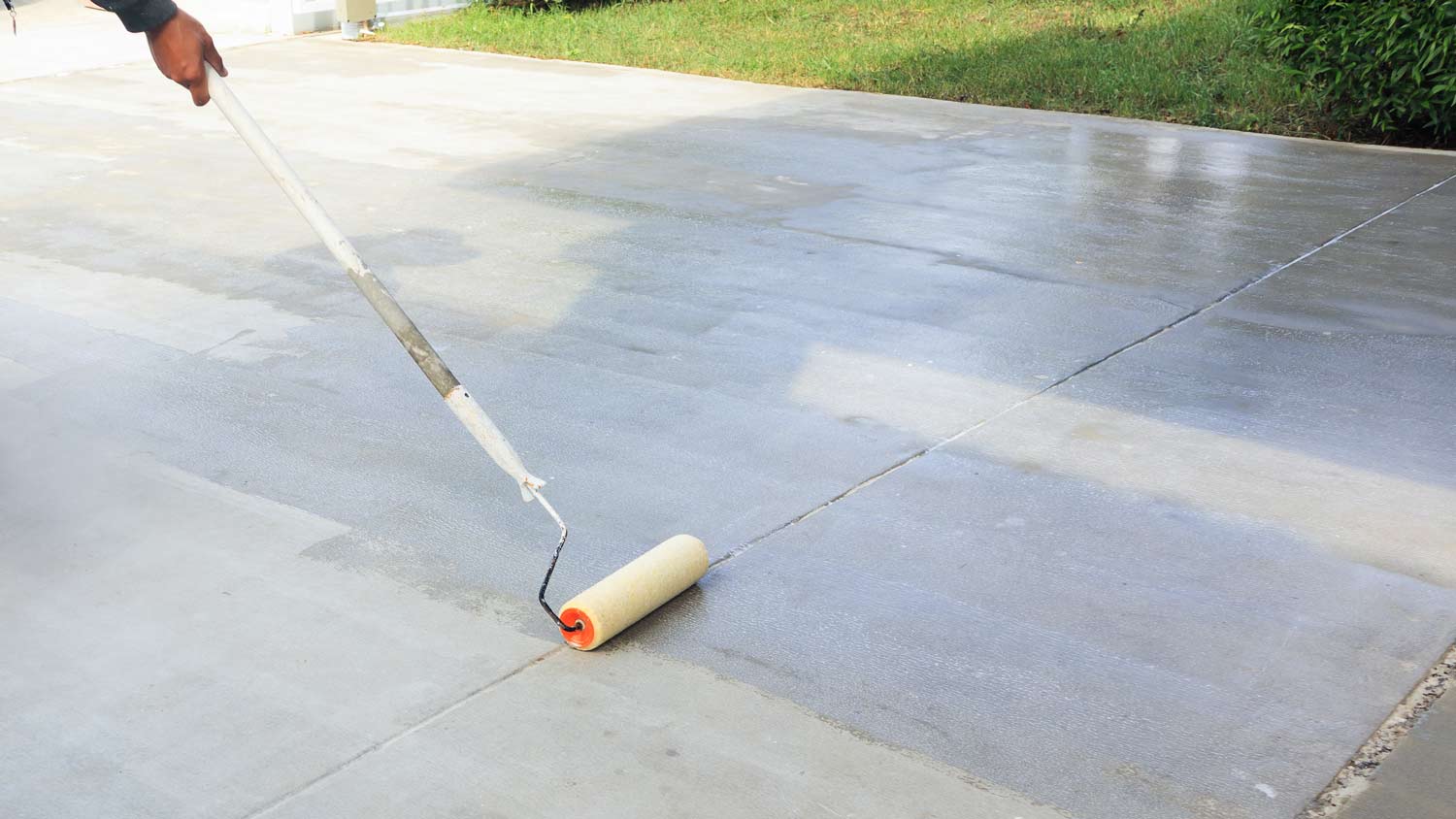 man staining concrete driveway