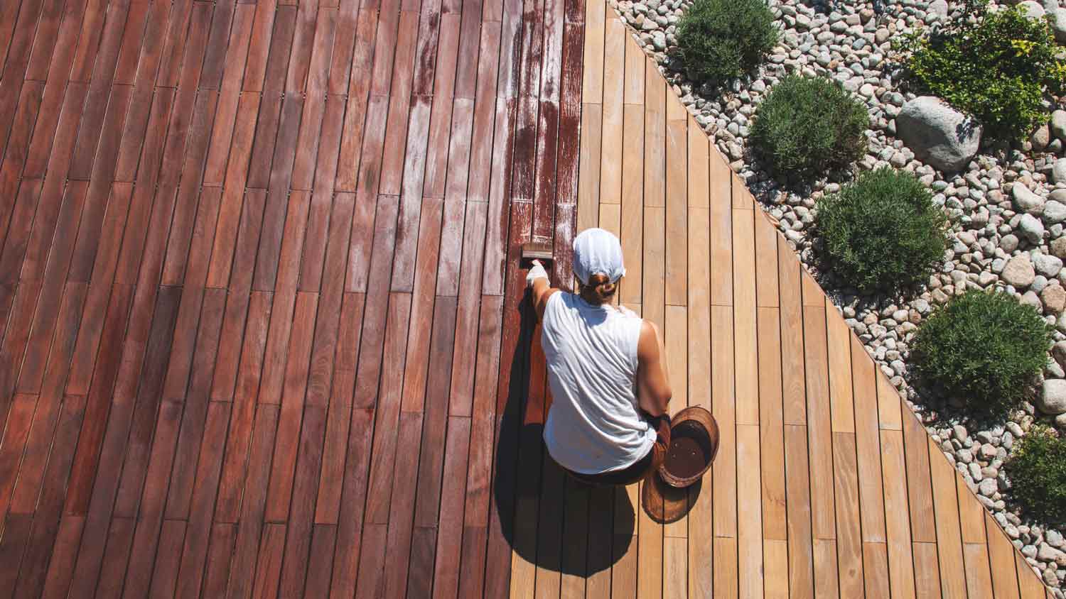 woman applying wood stain on deck