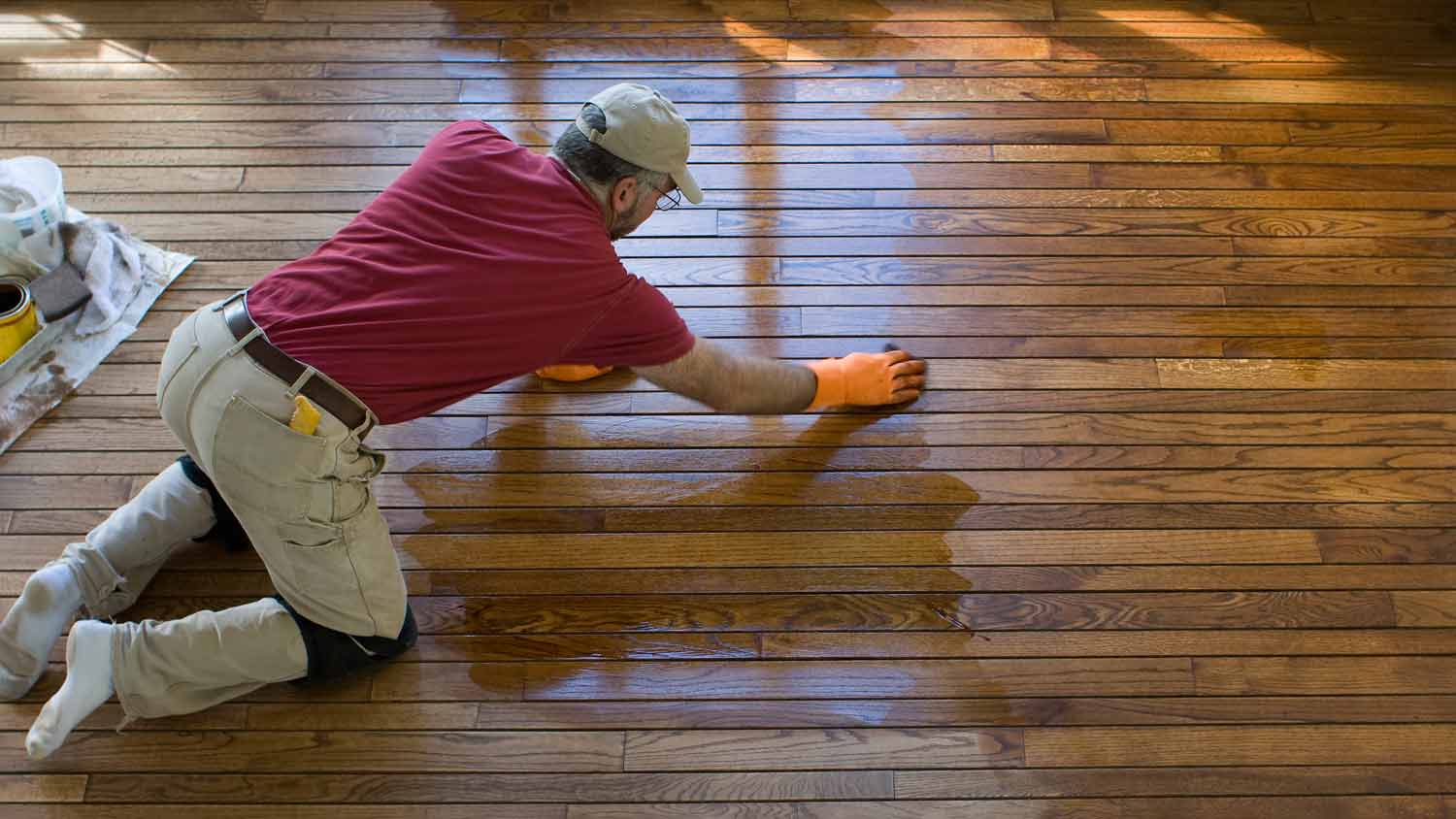 man staining wood floor 
