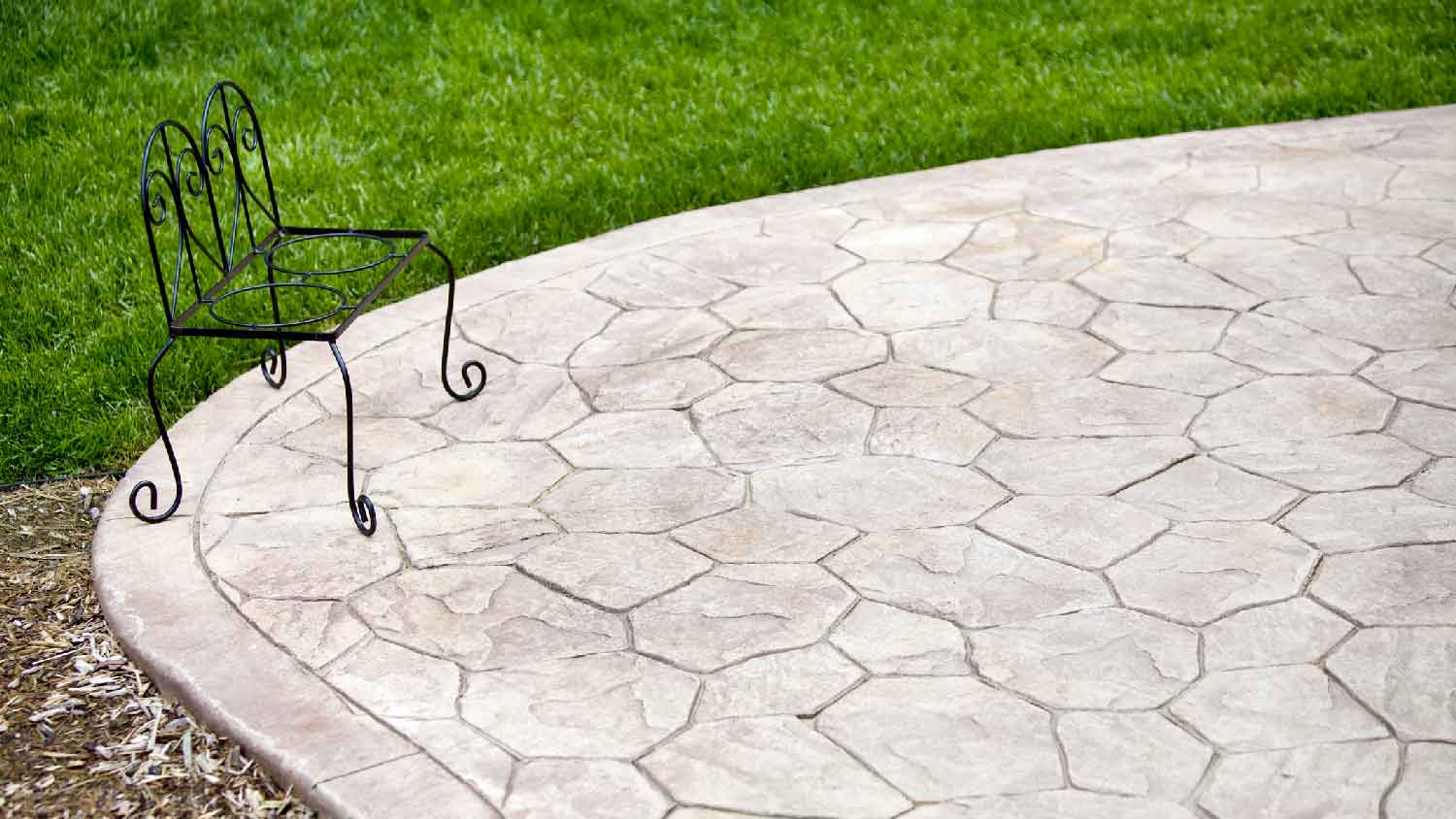 A stamped concrete patio with an iron bench