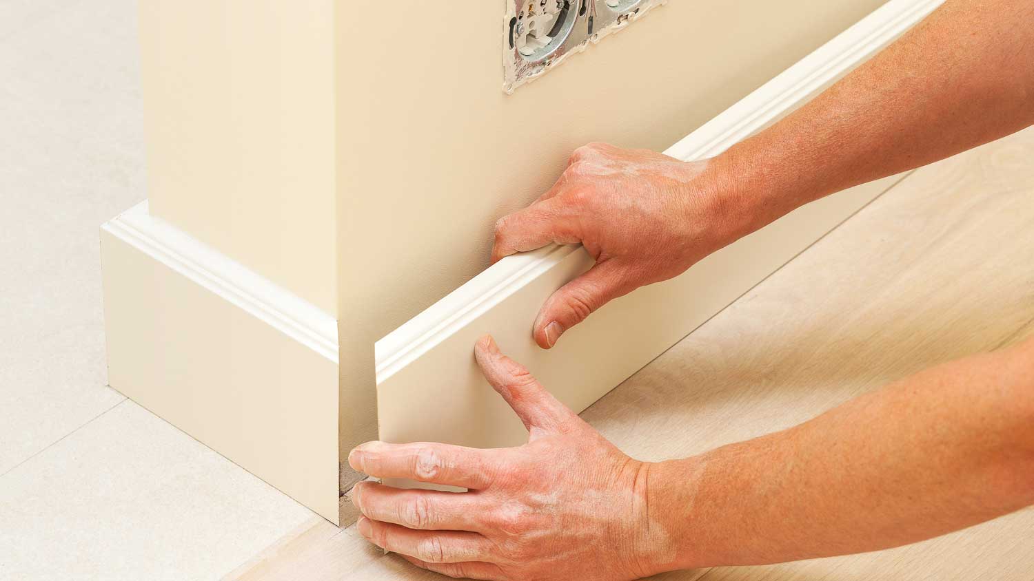 Worker installing stepped baseboard in the room