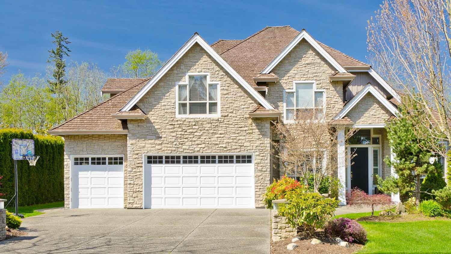 Large suburban house with stone veneer siding and concrete driveway