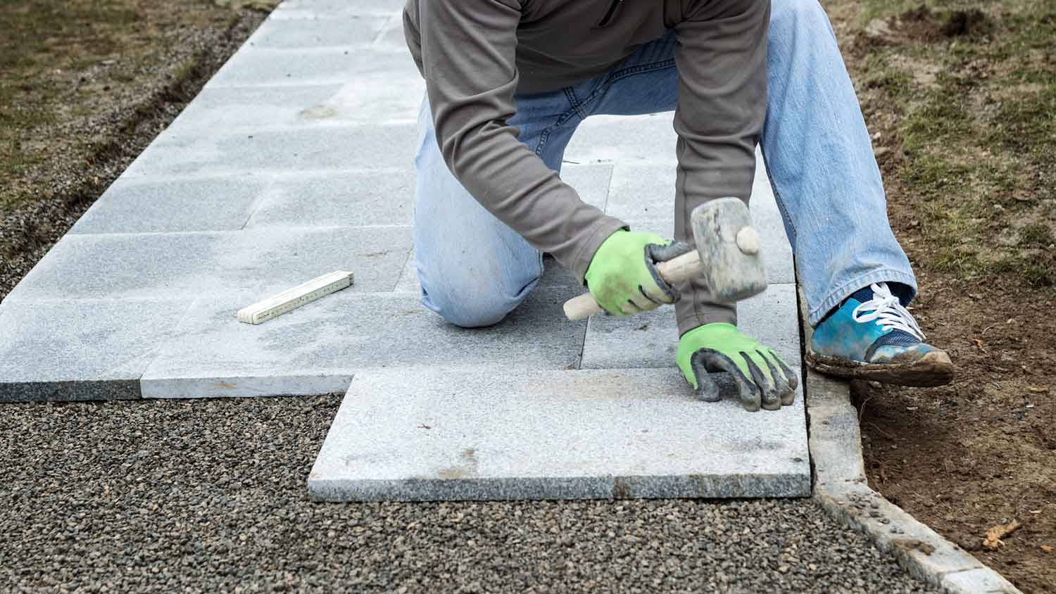 Worker installing stone walkway in the yard 