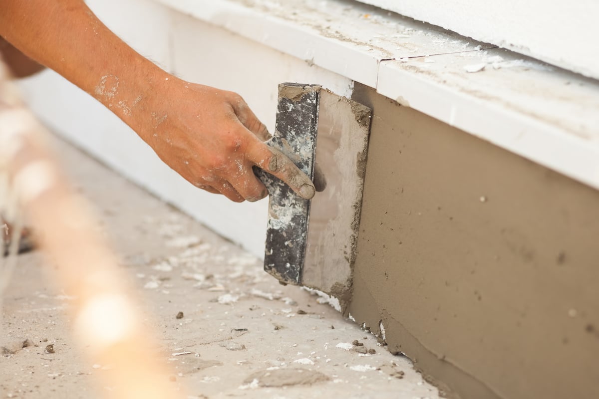 A man repairing stucco foundation