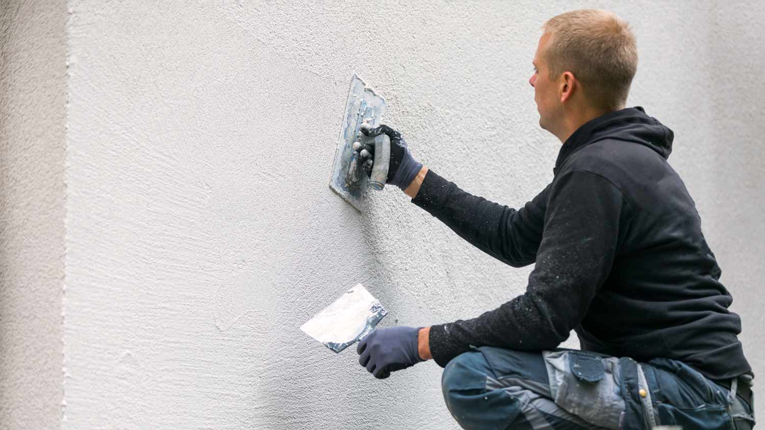 man applying plaster to house exterior