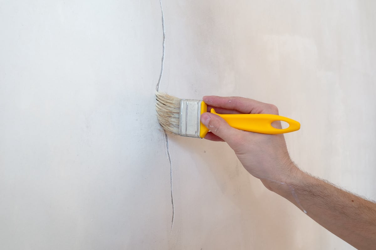 A man recoating stucco with a brush