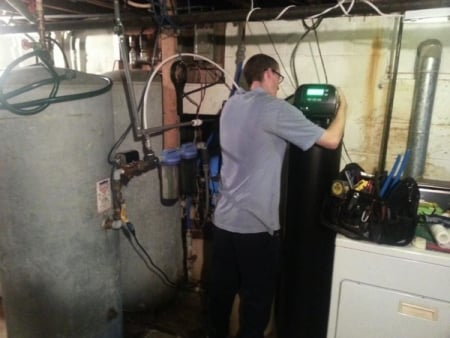 Service technician Jason Amerson installs a water softener in a Columbus-area home. (Photo courtesy of Robert Miller)
