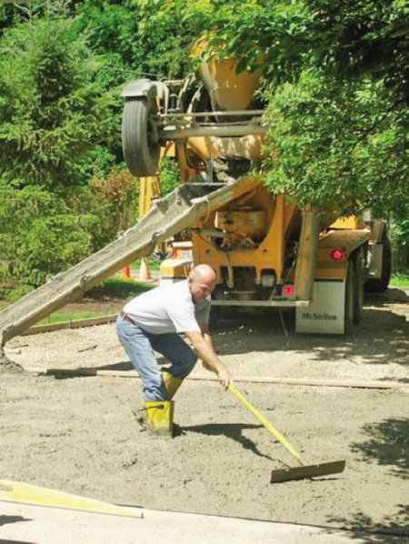 A construction worker smoothing out fresh concrete
