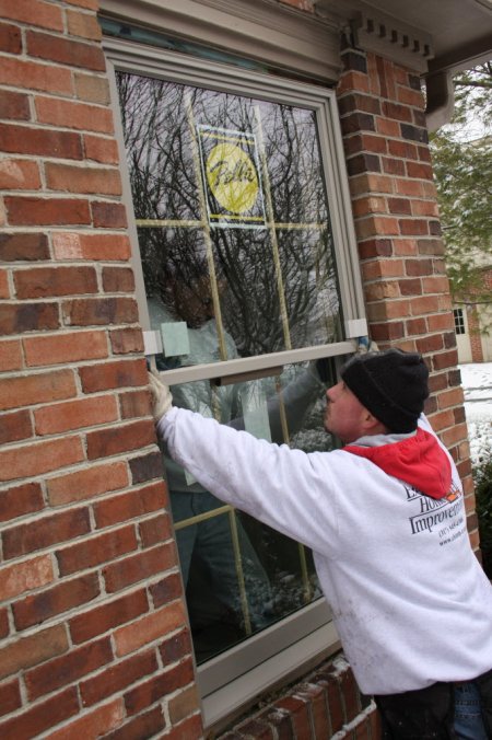 A man installing a window in a brick home