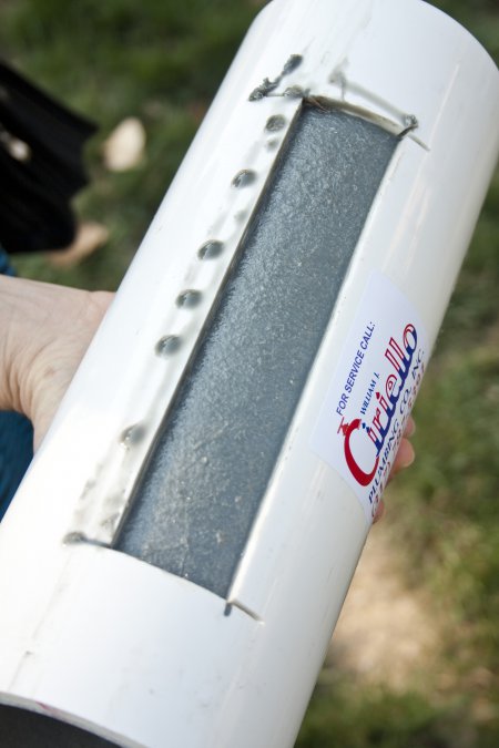 Piece of PVC pipe with cutout showing sewer liner inside