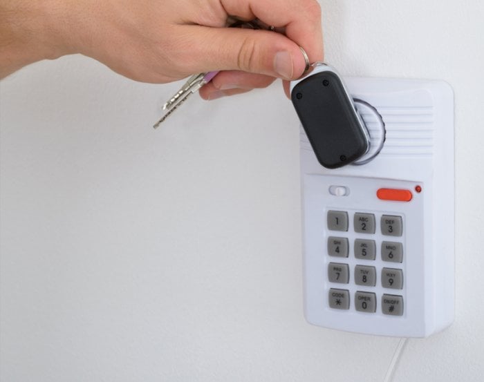 man holding key fob to communicate with house alarm