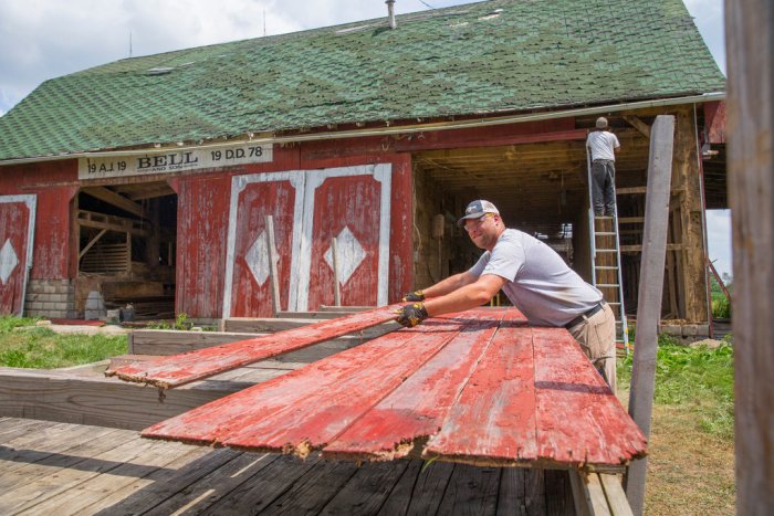 Hoosier Reclaimed Timber owner Adam Dick stacks wood from a barn in Kokomo, Indiana