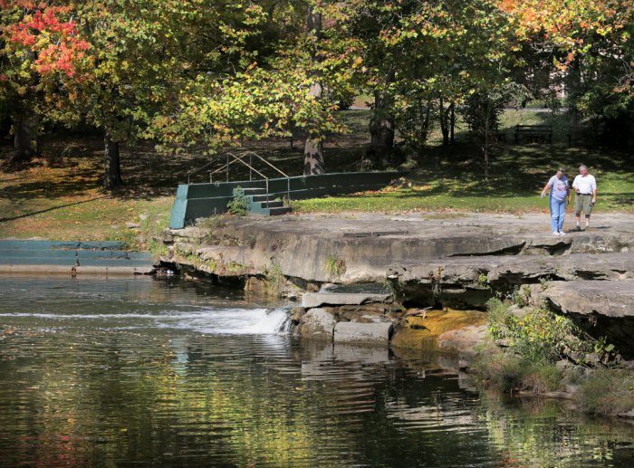 Two people walking along the falls at Falls Park in Pendleton, Indiana.