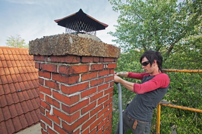 A contractor repairs the brick work on a chimney
