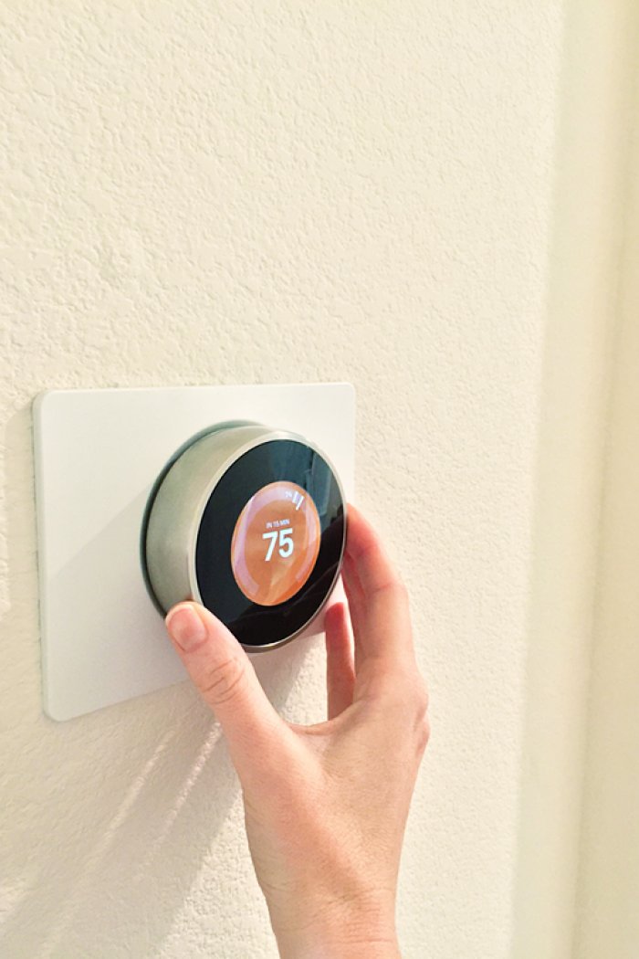 woman's hand adjust smart thermostat