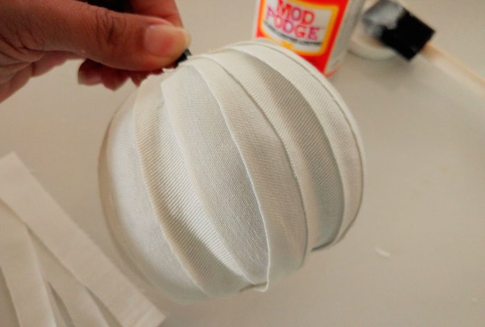 decoupaging white fabric strips to craft pumpkin