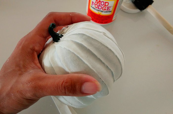 decoupaging white fabric strips to craft pumpkin