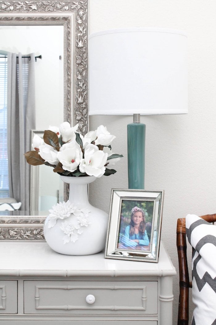 dresser tops with lamp, flowers, and photo of child